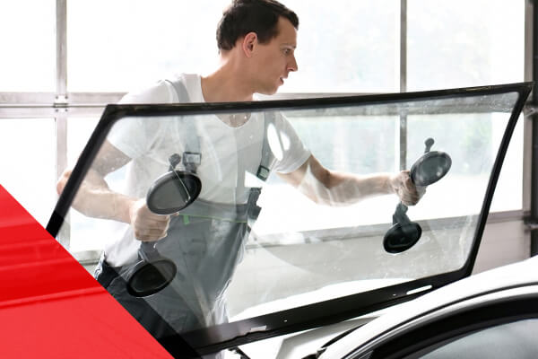 Auto glass repair expert putting a new windshield on a vehicle.