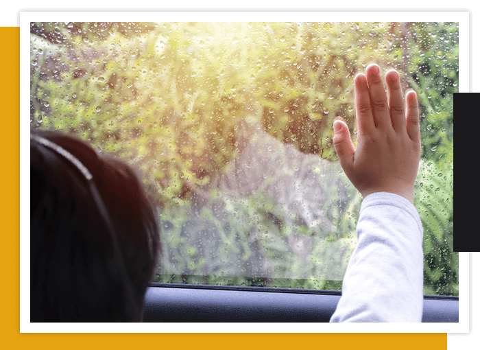 young girl looking out and touching car window